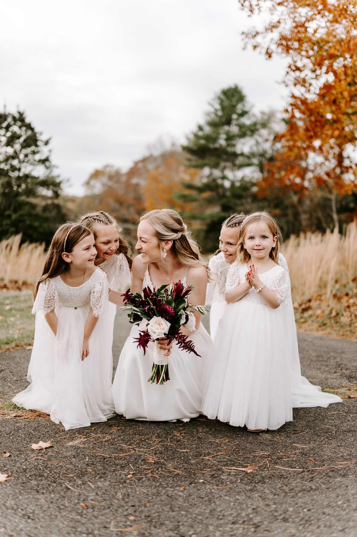 Flower girls in white dresses share joyful moment together during fall wedding photoshoot.