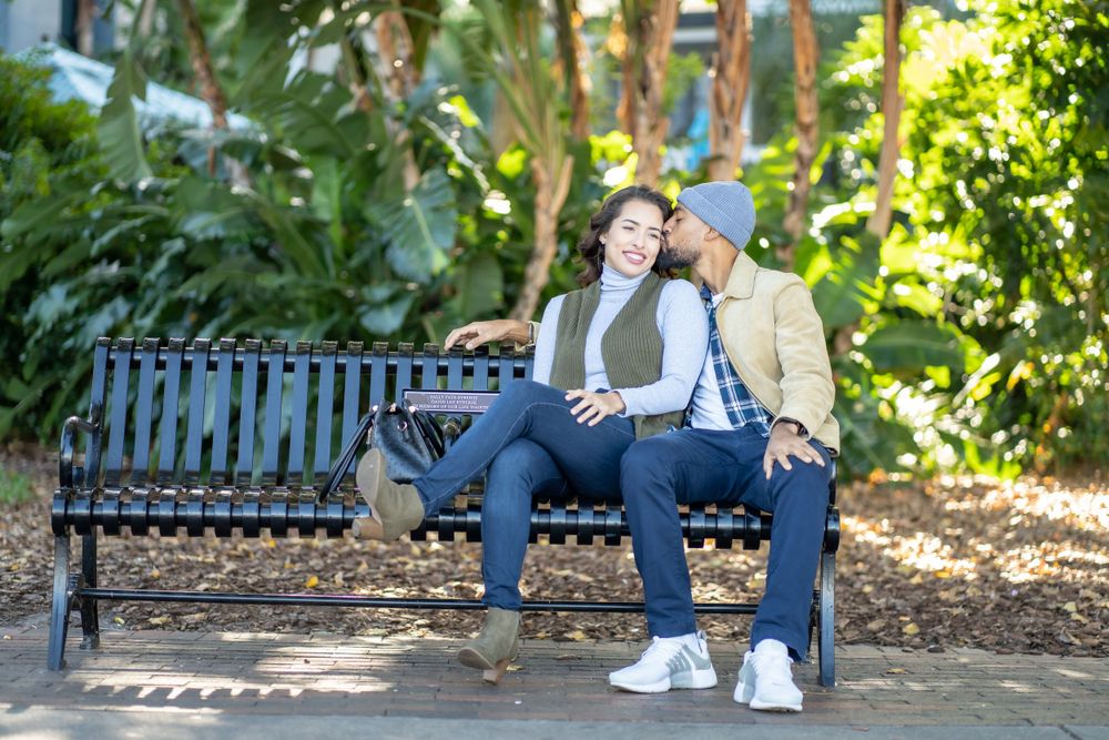A couple shares a sweet moment while sitting together on a park bench.