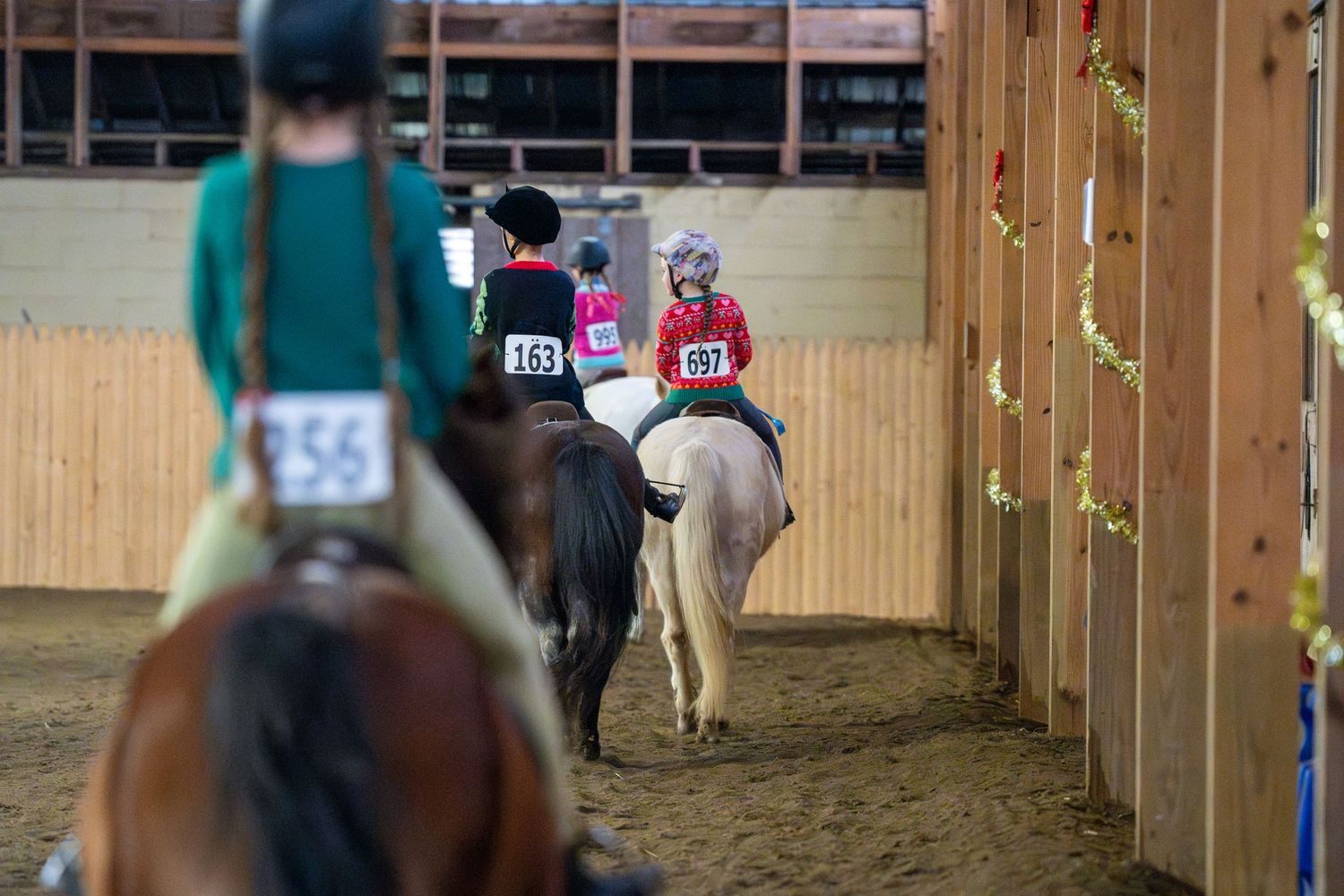 four kids riding horses away from camera