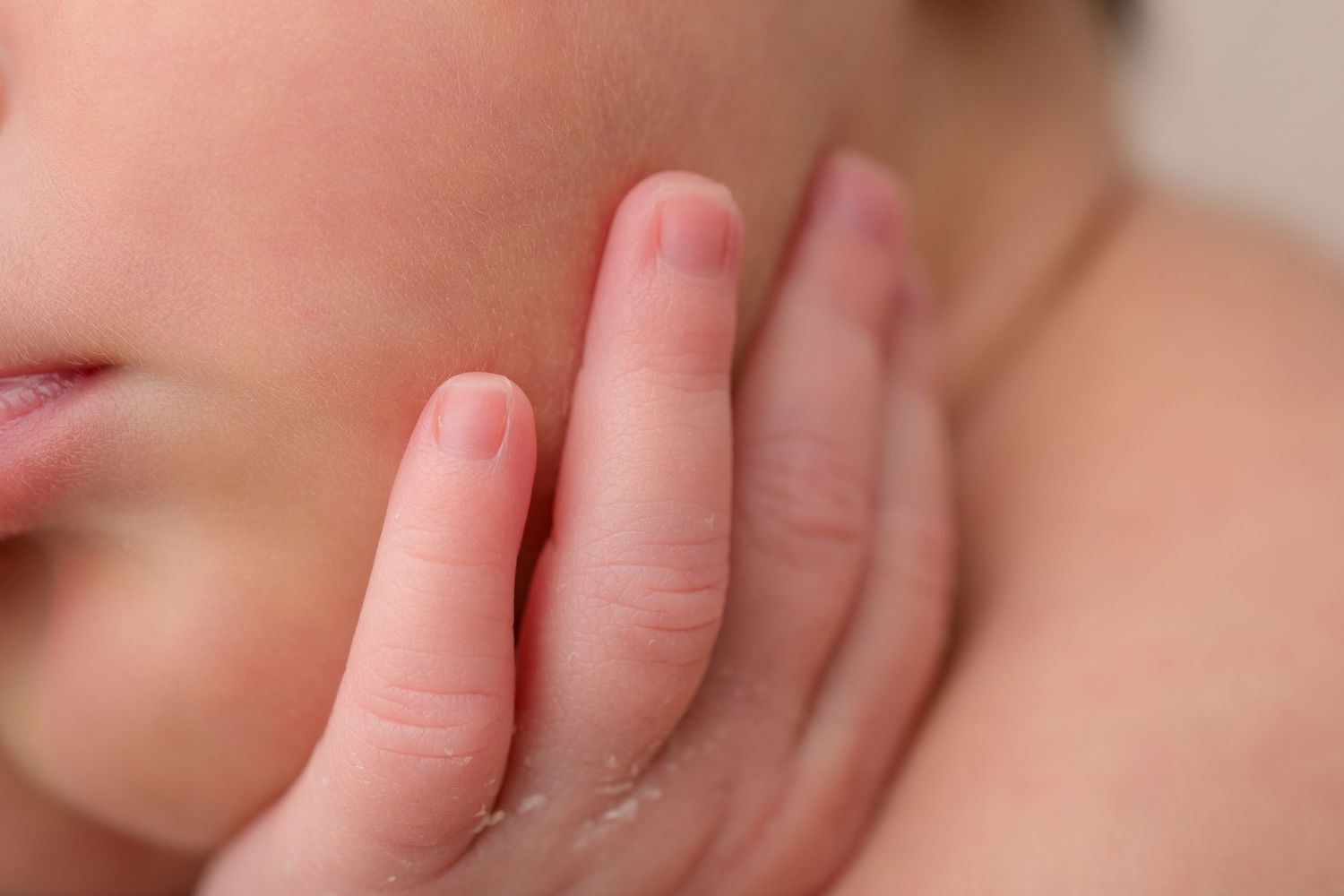 Extreme close-up of tiny newborn baby fingers against soft skin.