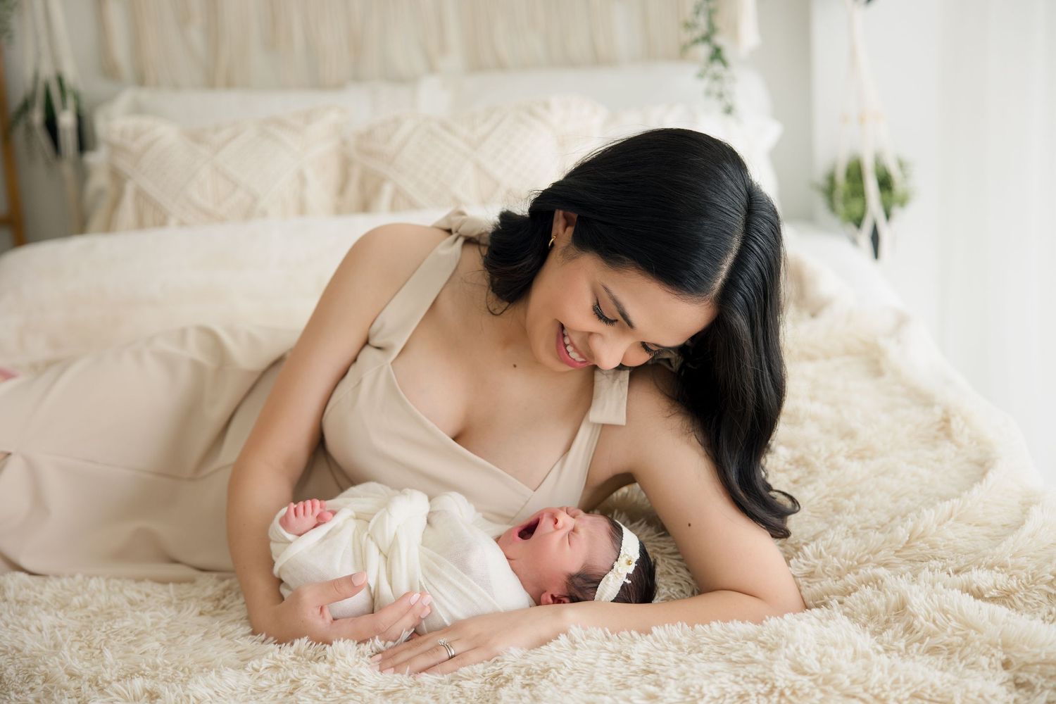 Parent and newborn sharing a loving moment together on a cozy white bed.