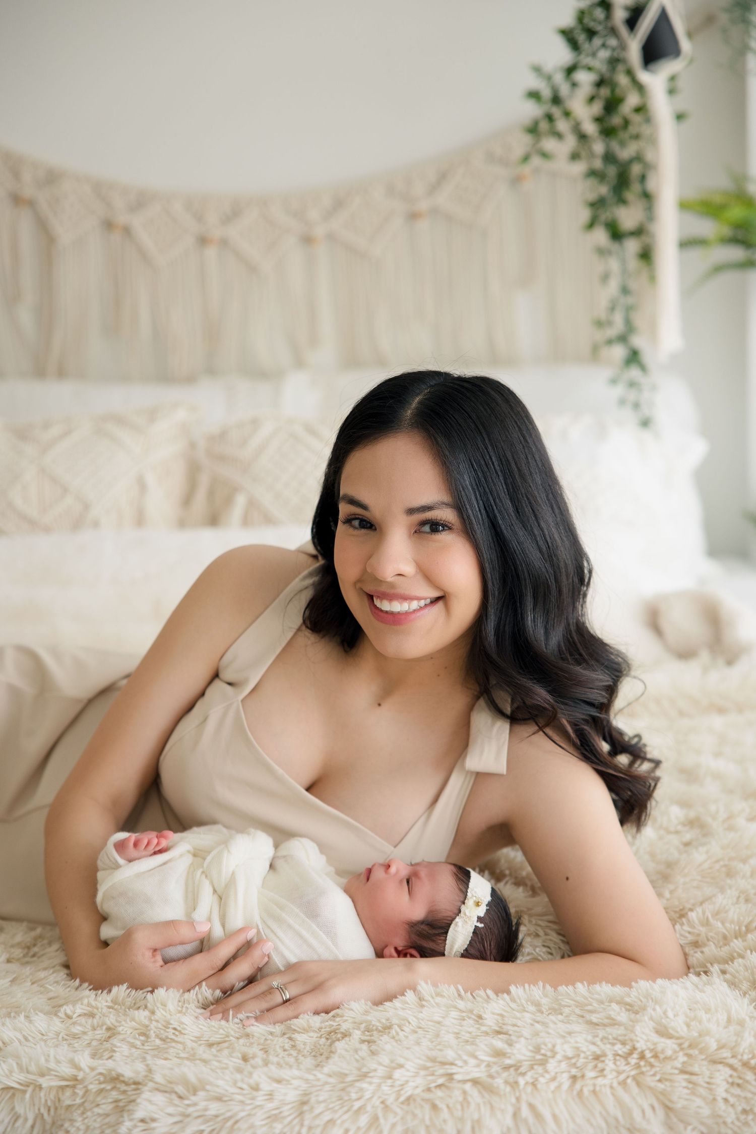 Parent and infant sharing a joyful moment while lying on plush white bedding.