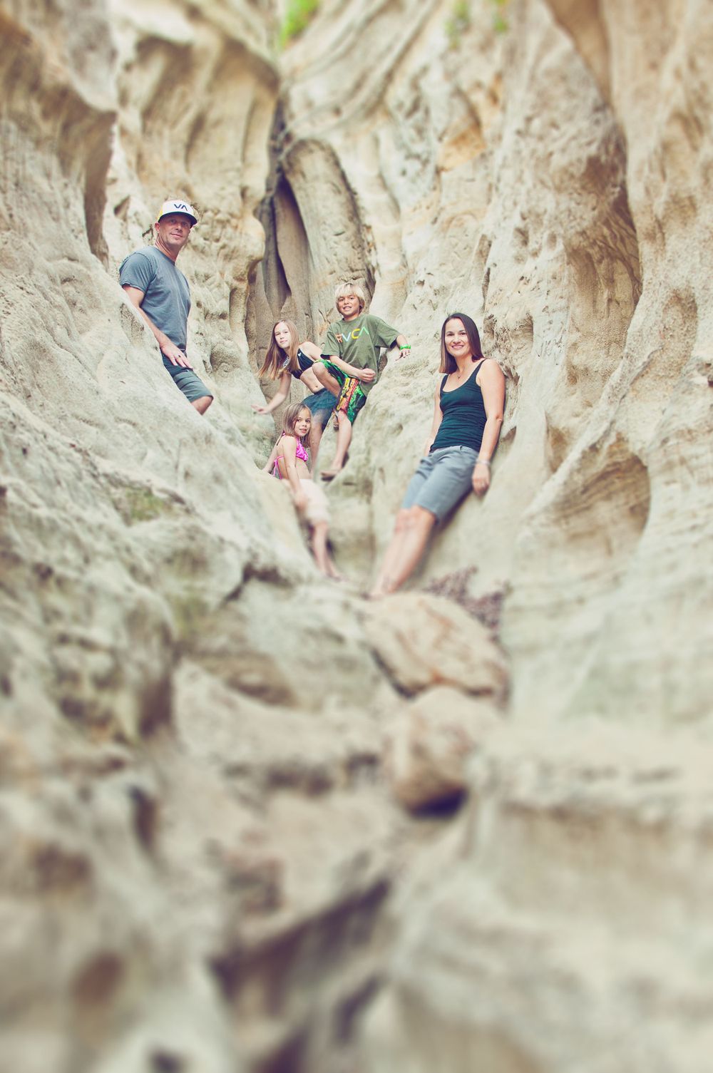 Family of five posing among dramatic eroded rock formations in a narrow canyon.