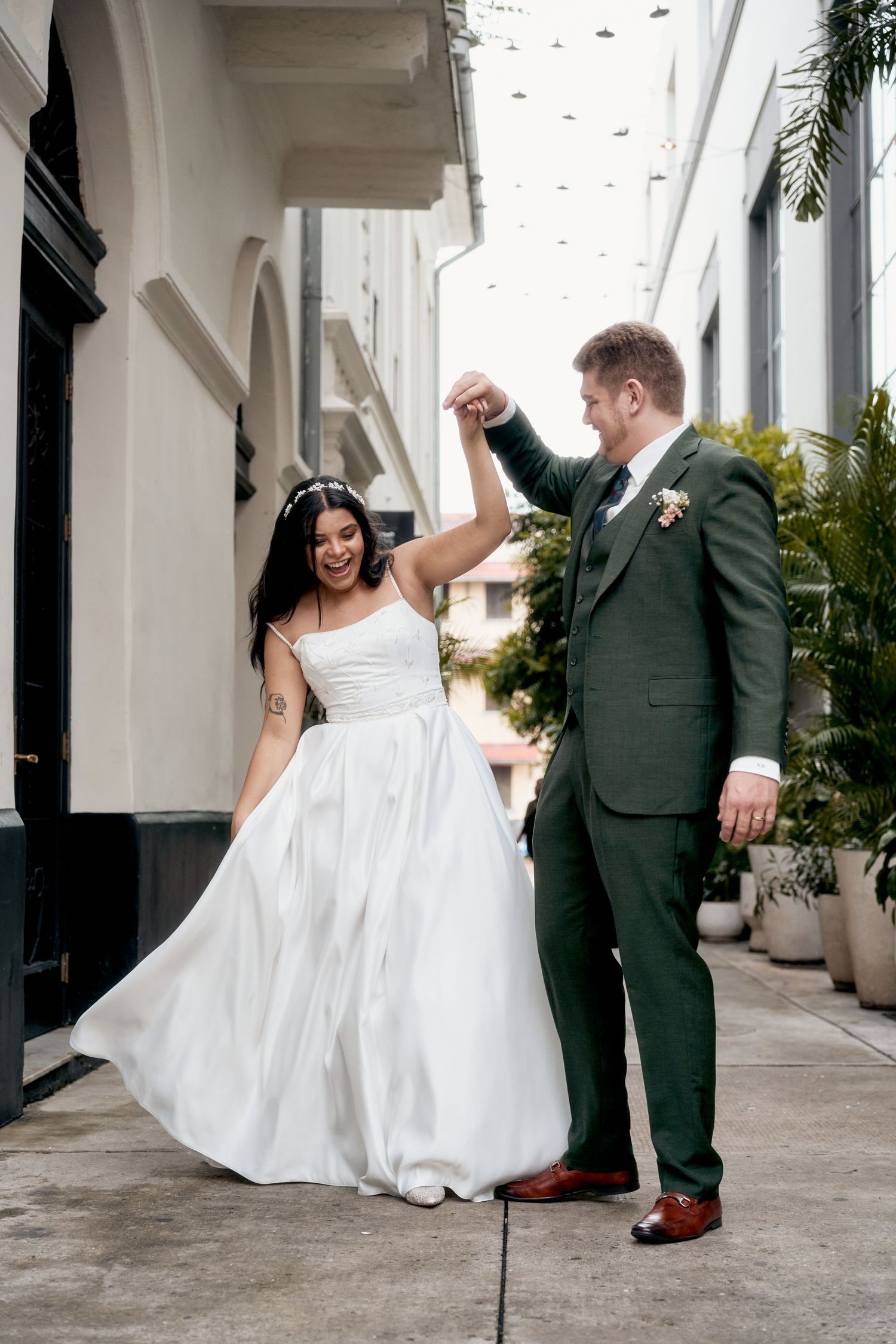 A couple dancing and twirling in formal wedding attire on an outdoor patio.