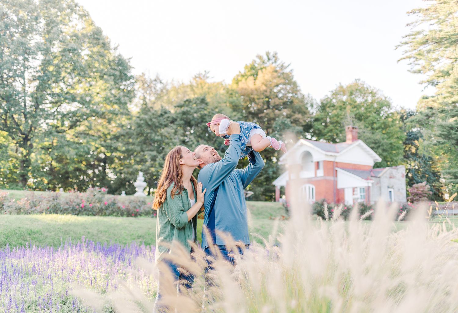 Family smiling at each other in a flower garden during a family session in Hyde Park, NY