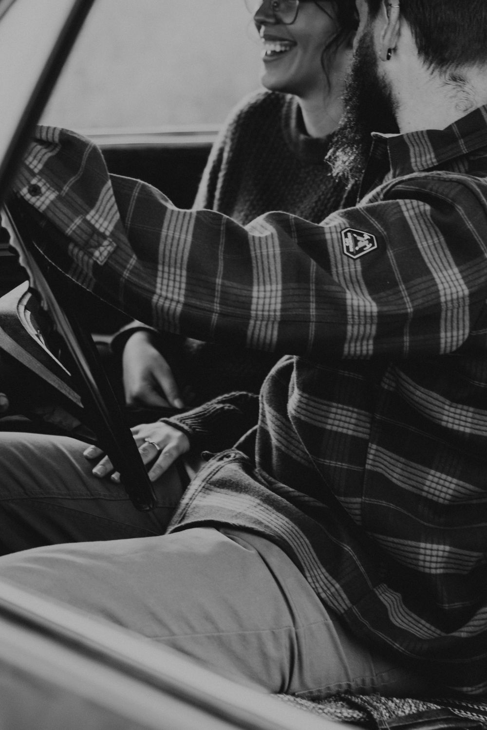Black and white photo of people laughing together in a car wearing plaid.
