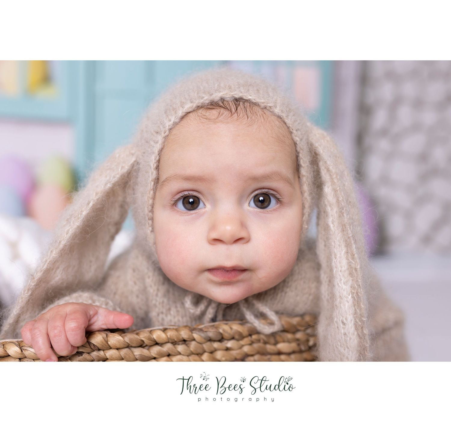 Artistic portrait with soft beige bunny hood against pastel backdrop.