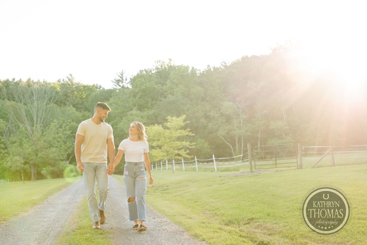 Couple walking together on country path during sunset in pastoral setting.