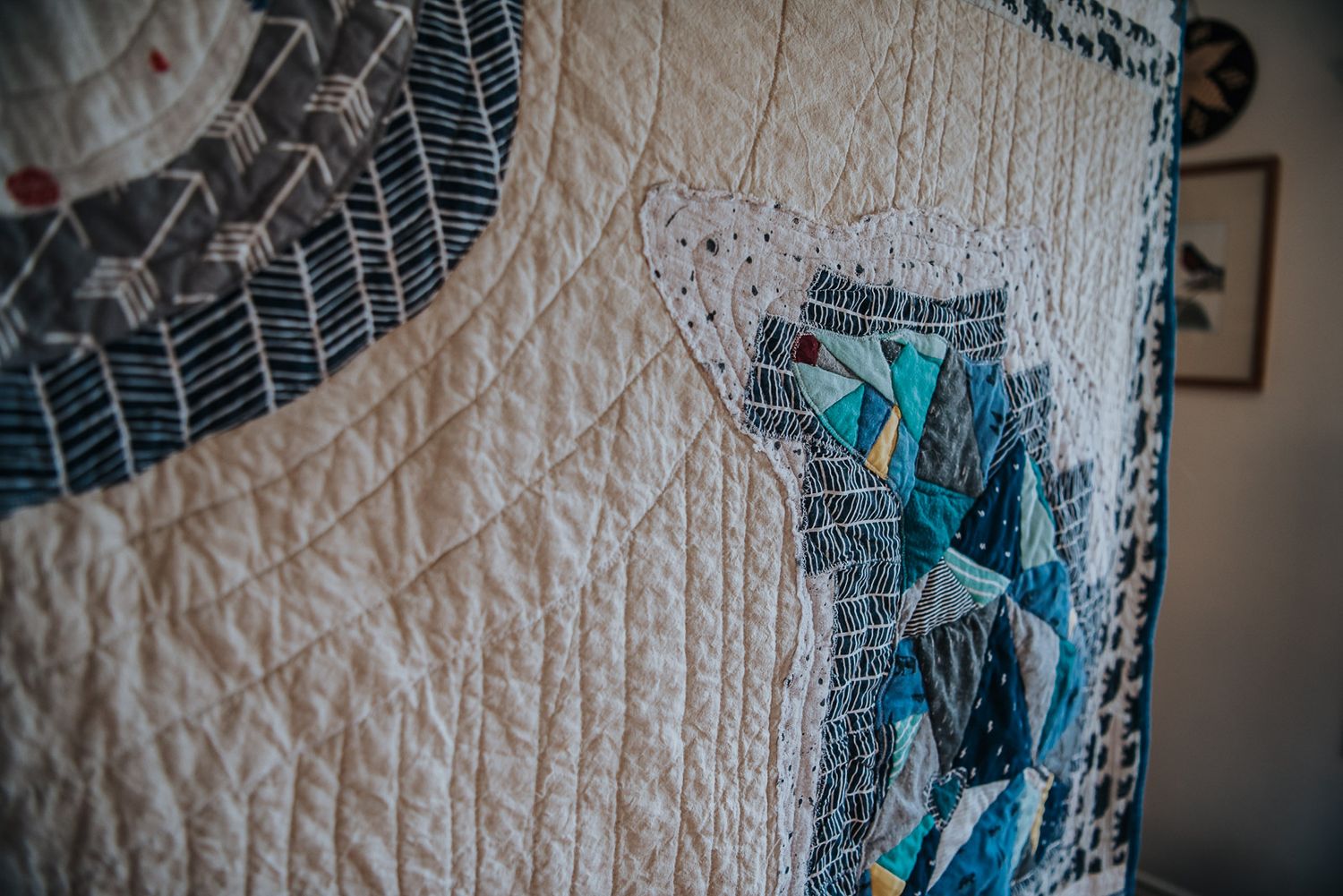 A textured memory quilt is held up showcasing a bear made of many shades of blue clothing.