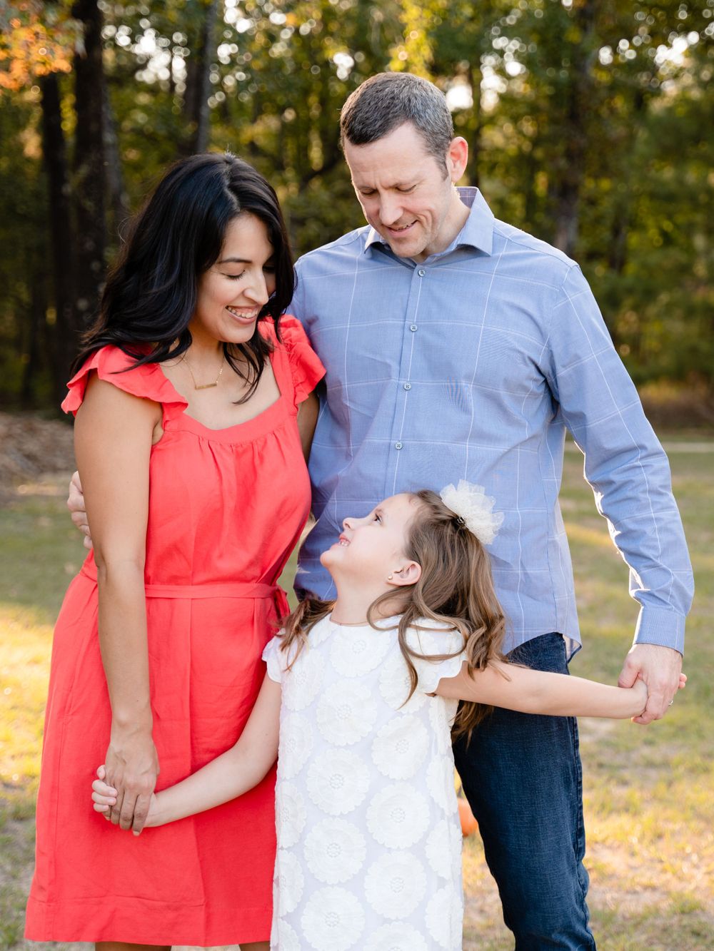 Family shares candid laughing moment together during golden hour portrait session.