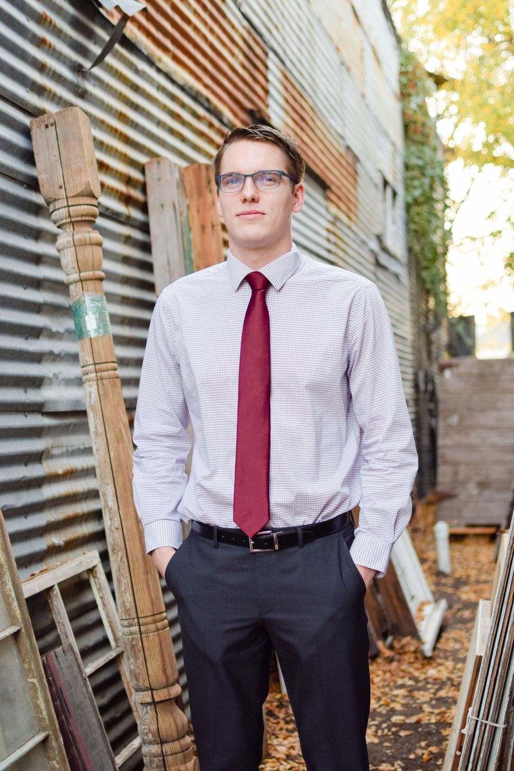 Professional portrait of businessman in tie standing against industrial metal wall background.