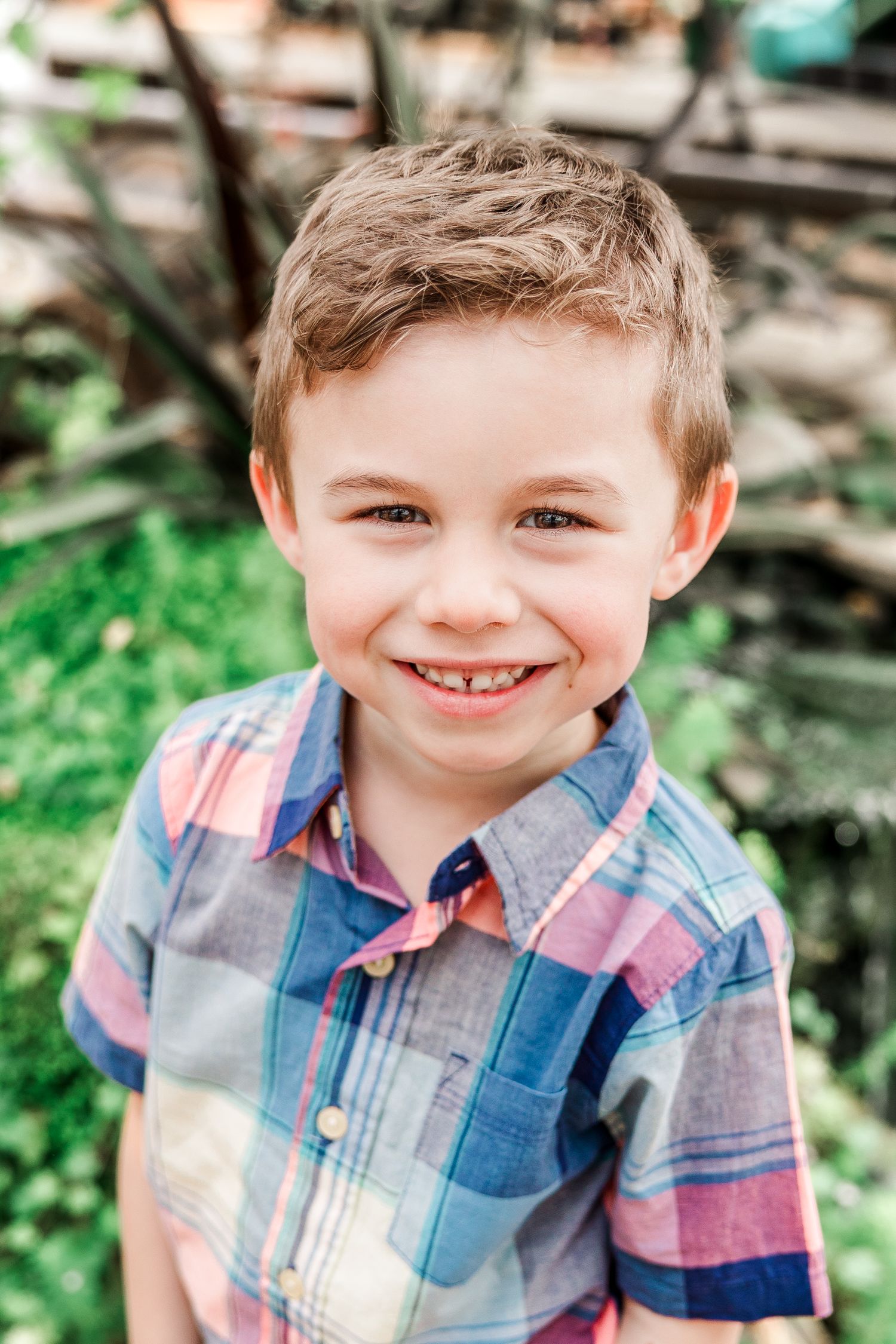 A cheerful figure in a plaid shirt poses against a blurred green background.