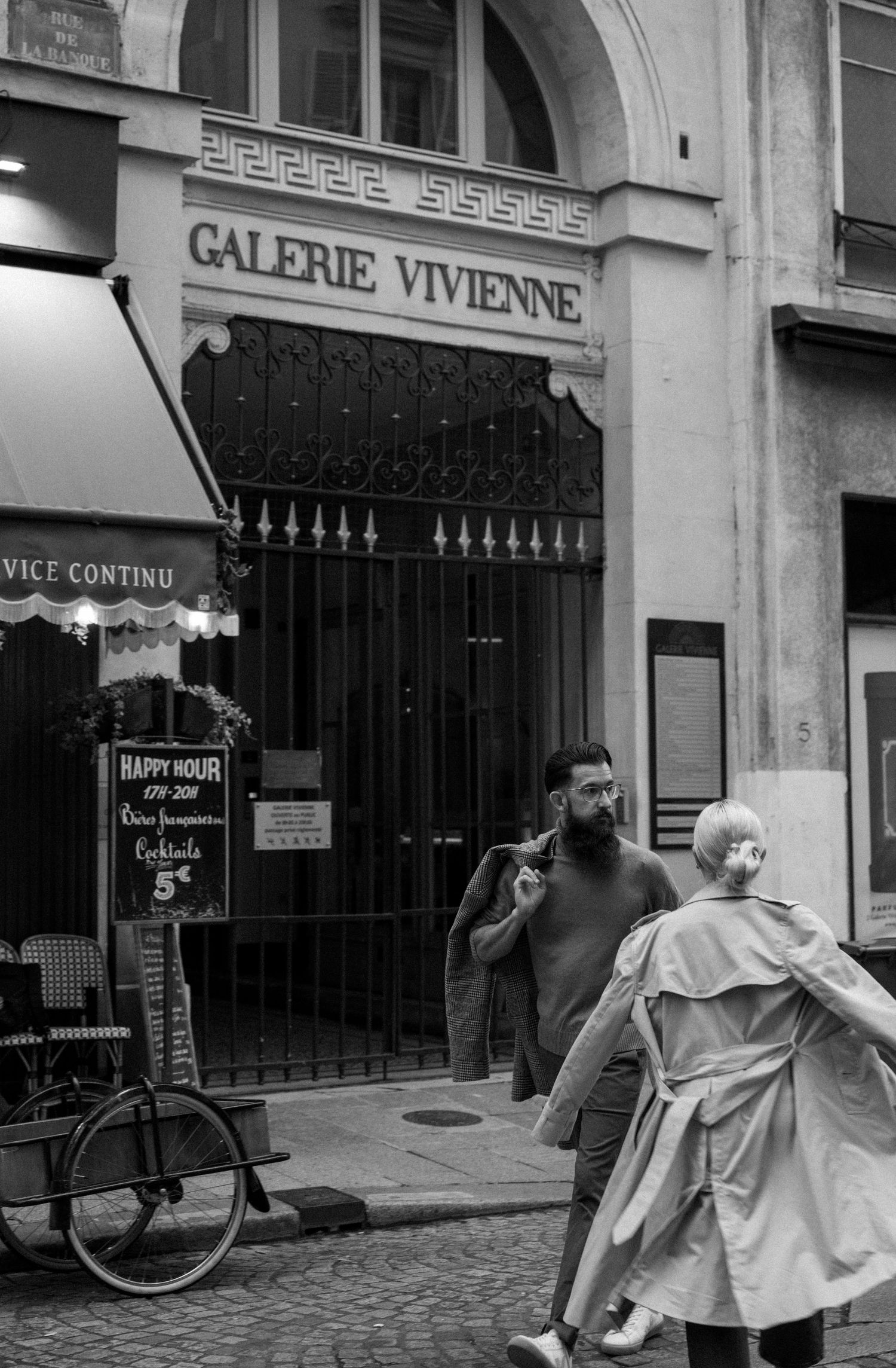 Black and white street scene outside the historic Galerie Vivienne in Paris.