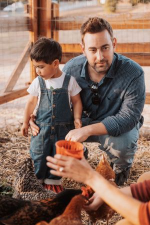 A tender moment feeding chickens in an outdoor coop setting.