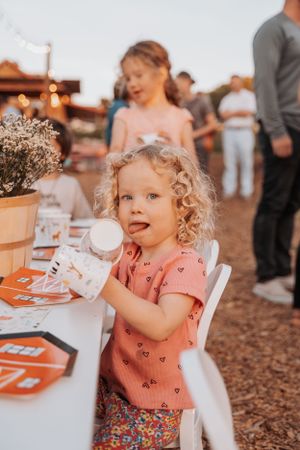 Young child enjoying treats at an outdoor party table with decorations.