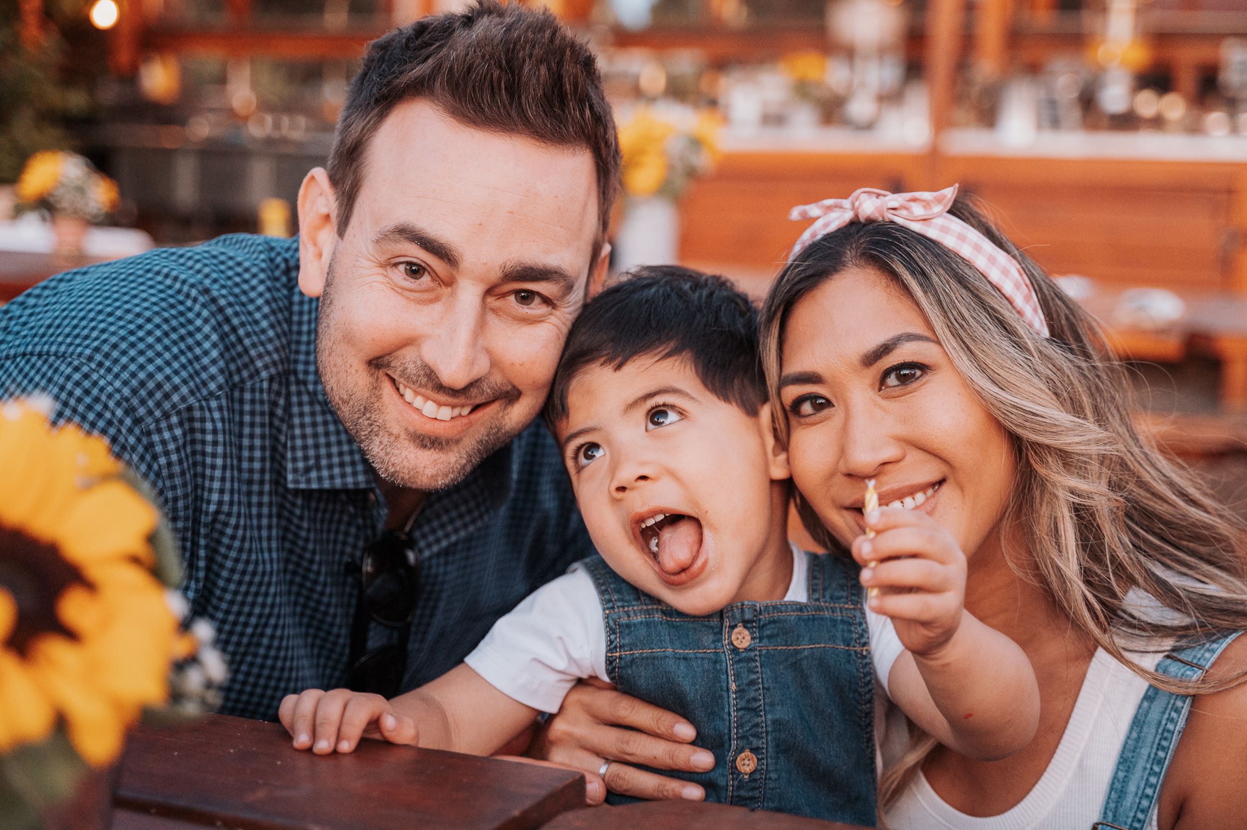 Family enjoying a fun moment together at an outdoor event with sunflowers.