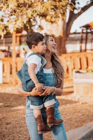A heartwarming moment in denim overalls and boots against a golden sunset backdrop at a farm.