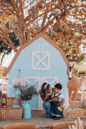 A small blue barn playhouse decorated for a party with autumn trees and decorative horse statue.