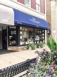 Charming bookstore storefront with blue awning and flower planters along sidewalk.