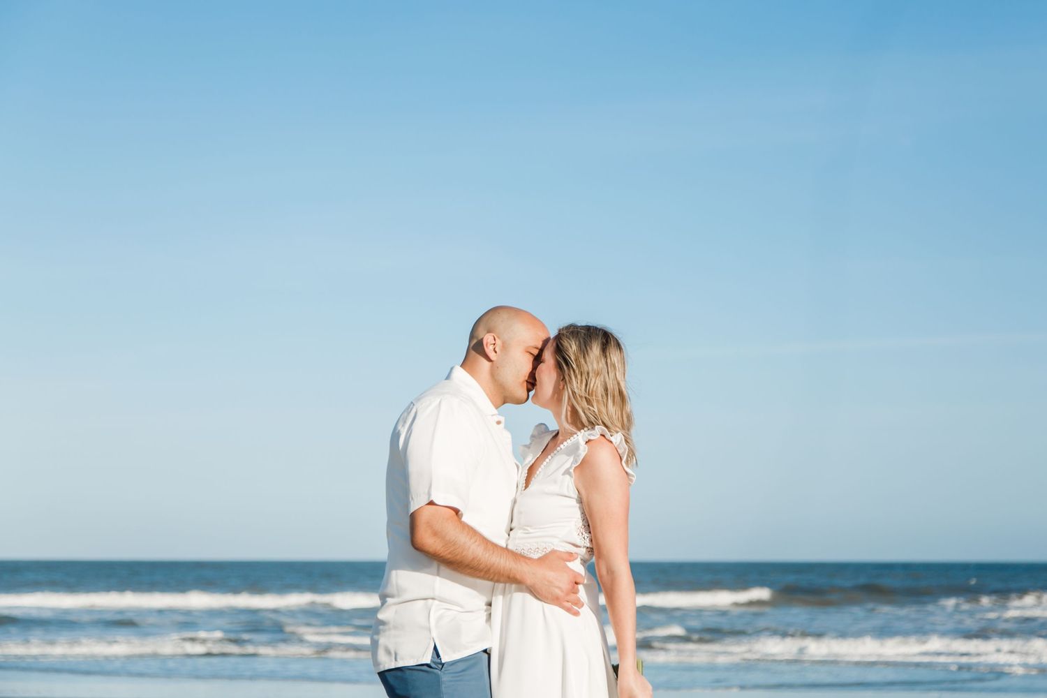 Romantic beachside moment with white-dressed couple against ocean backdrop Atlantic City, NJ.