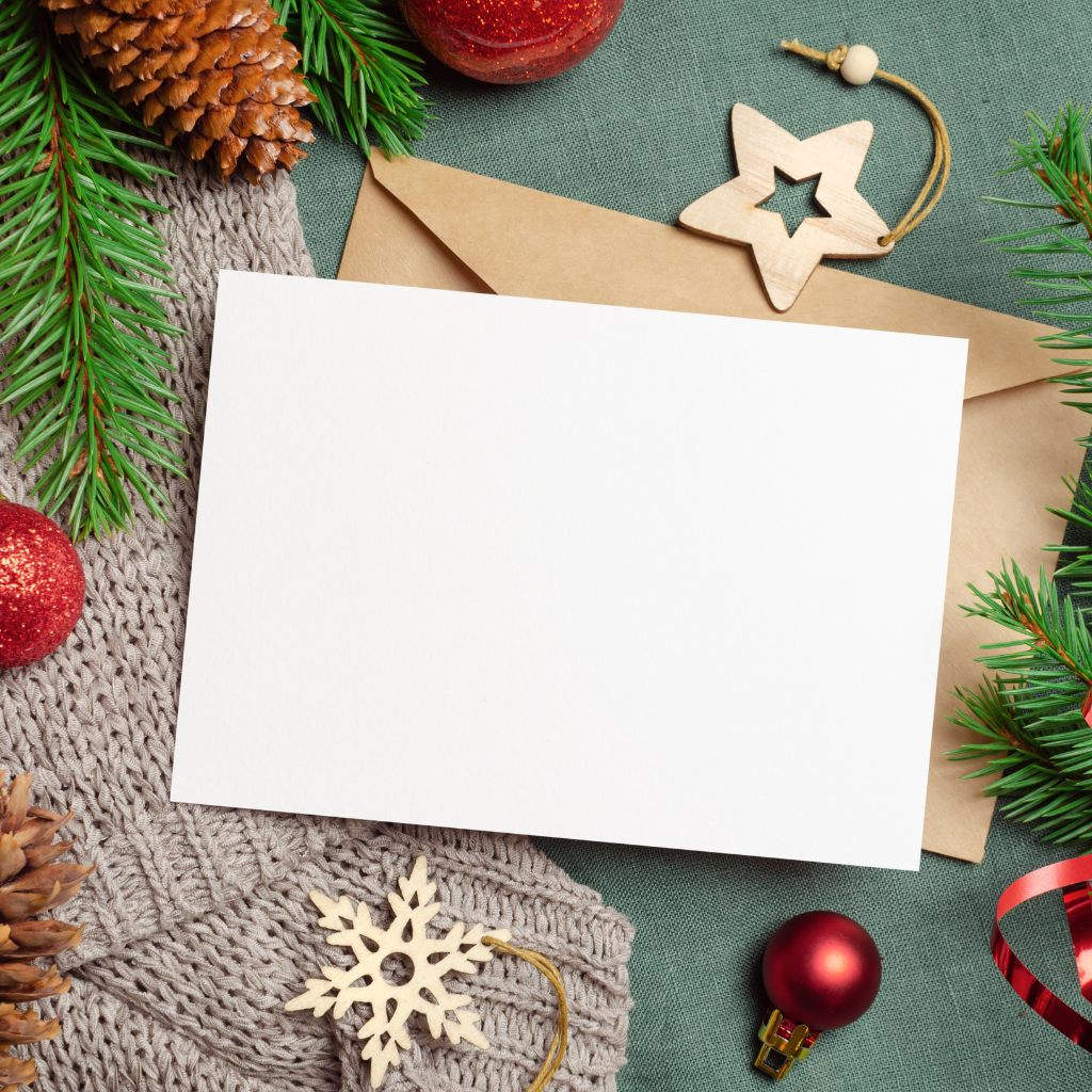 Blank white card mockup with rustic Christmas decorations including pinecone, evergreen sprigs and ornaments.