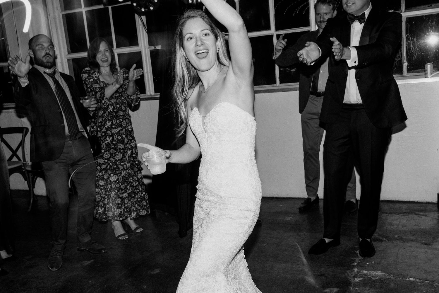 Bride in fitted white dress dancing joyfully at wedding reception.