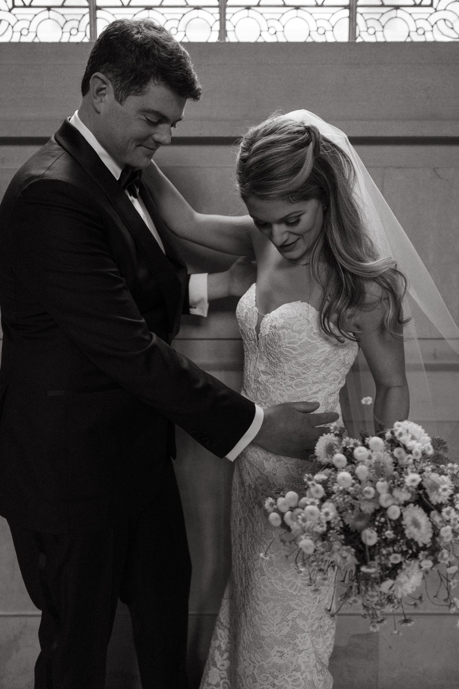 An intimate black and white wedding portrait featuring a couple with a beautiful floral bouquet.