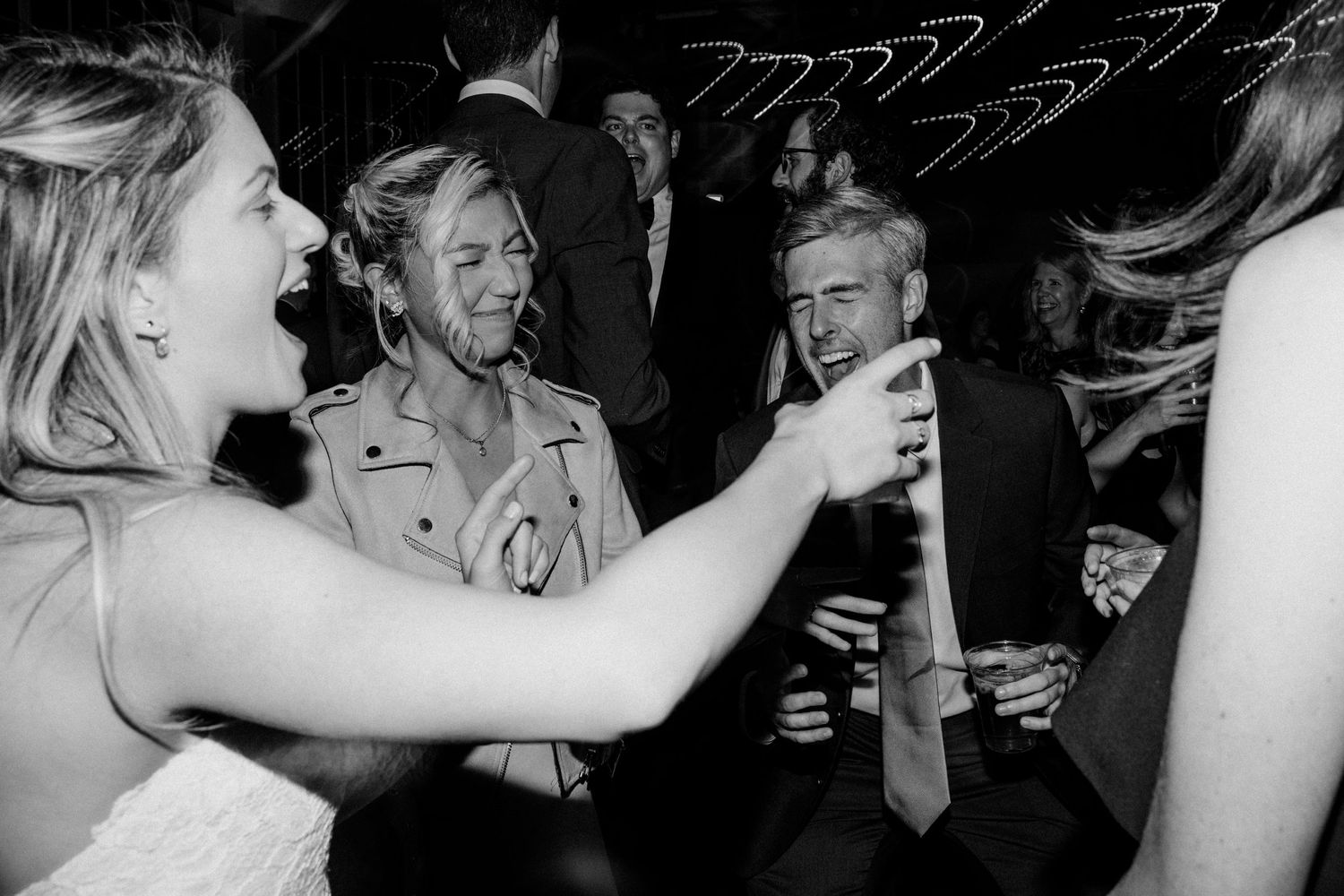 Black and white photo of party guests laughing and celebrating with drinks.