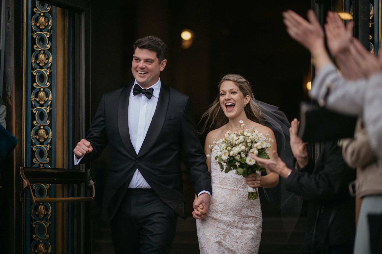 Joyful exit from City Hall wedding ceremony with guests clapping.