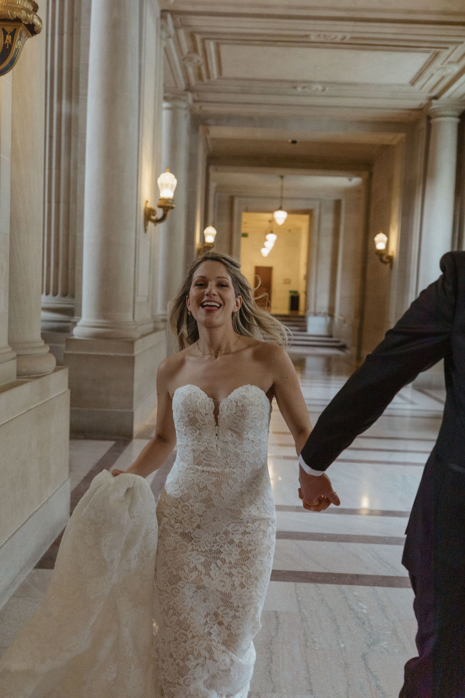 A joyful moment in an elegant marble hallway with classical architectural details.