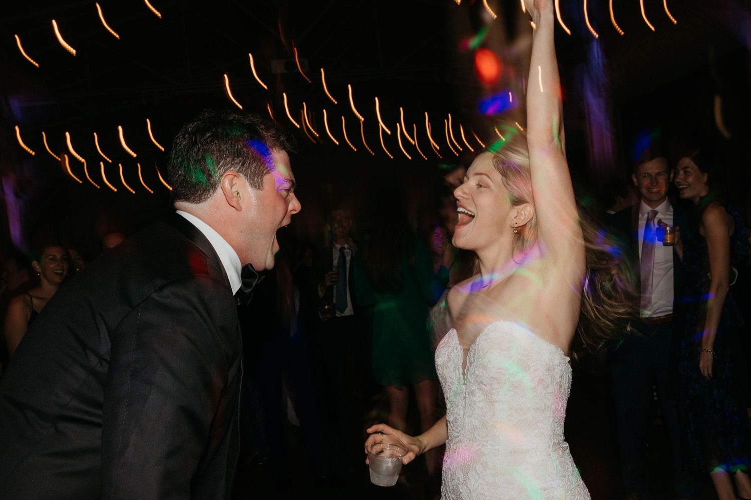 An enthusiastic couple celebrates on the dance floor at their wedding reception.