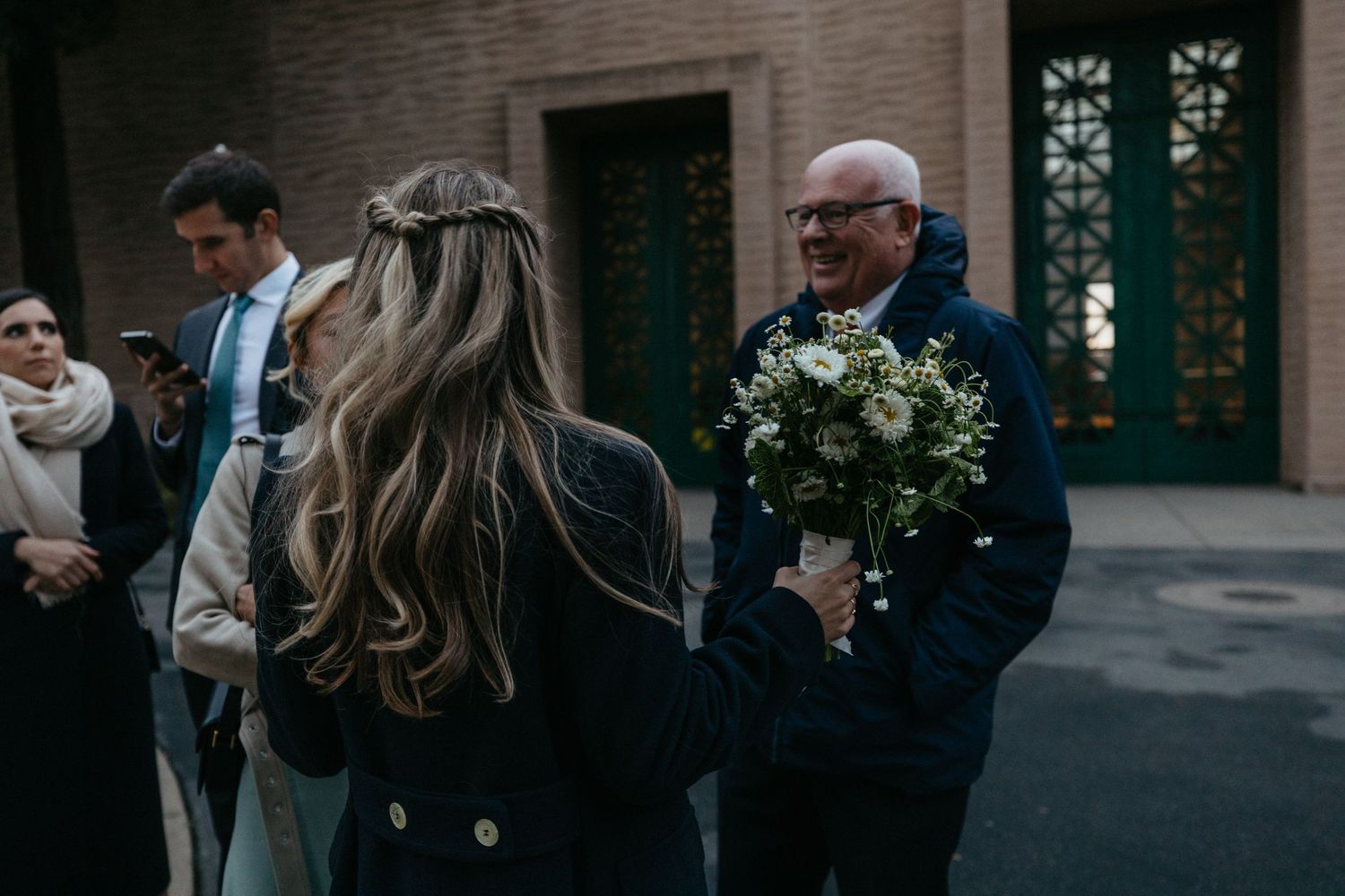 Wedding guests gather outside a building with a distinctive teal door.