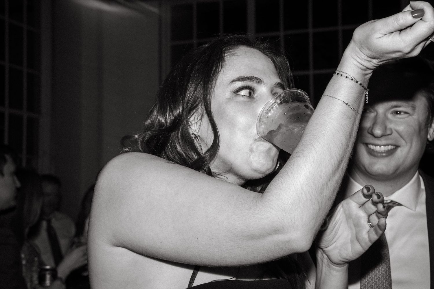 A person takes a celebratory drink while dancing at a party.