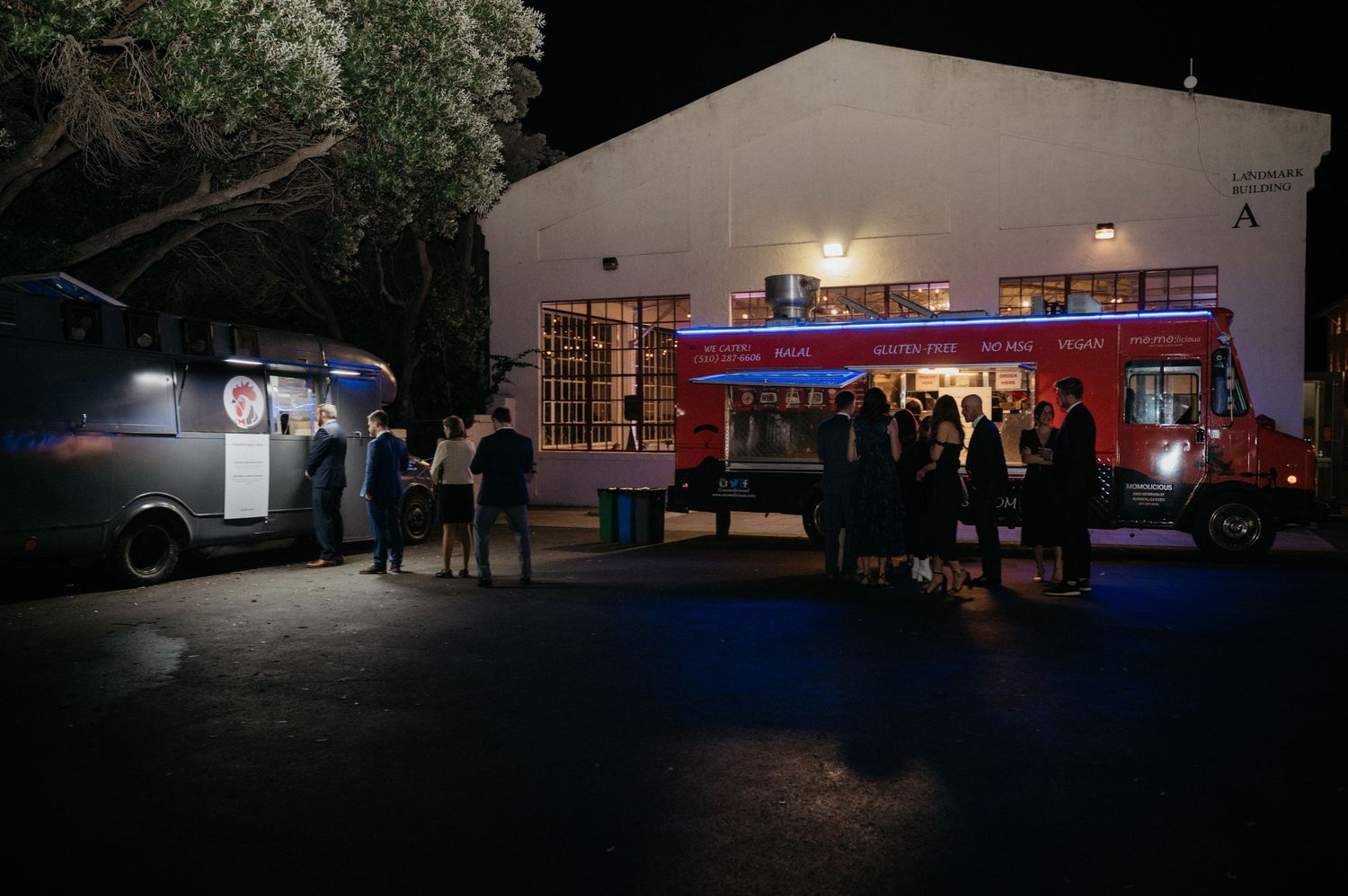 Food trucks illuminate a dark parking lot as wedding guests gather for late-night snacks.