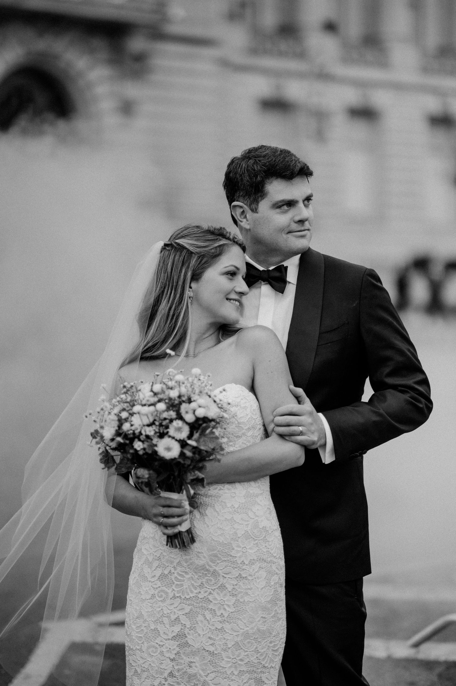 A couple poses for a formal wedding portrait outside a grand building.