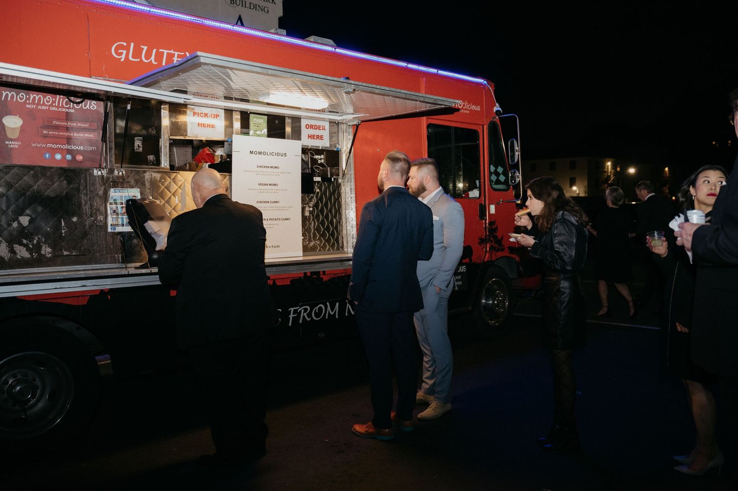 A food truck serves guests at a nighttime wedding reception.