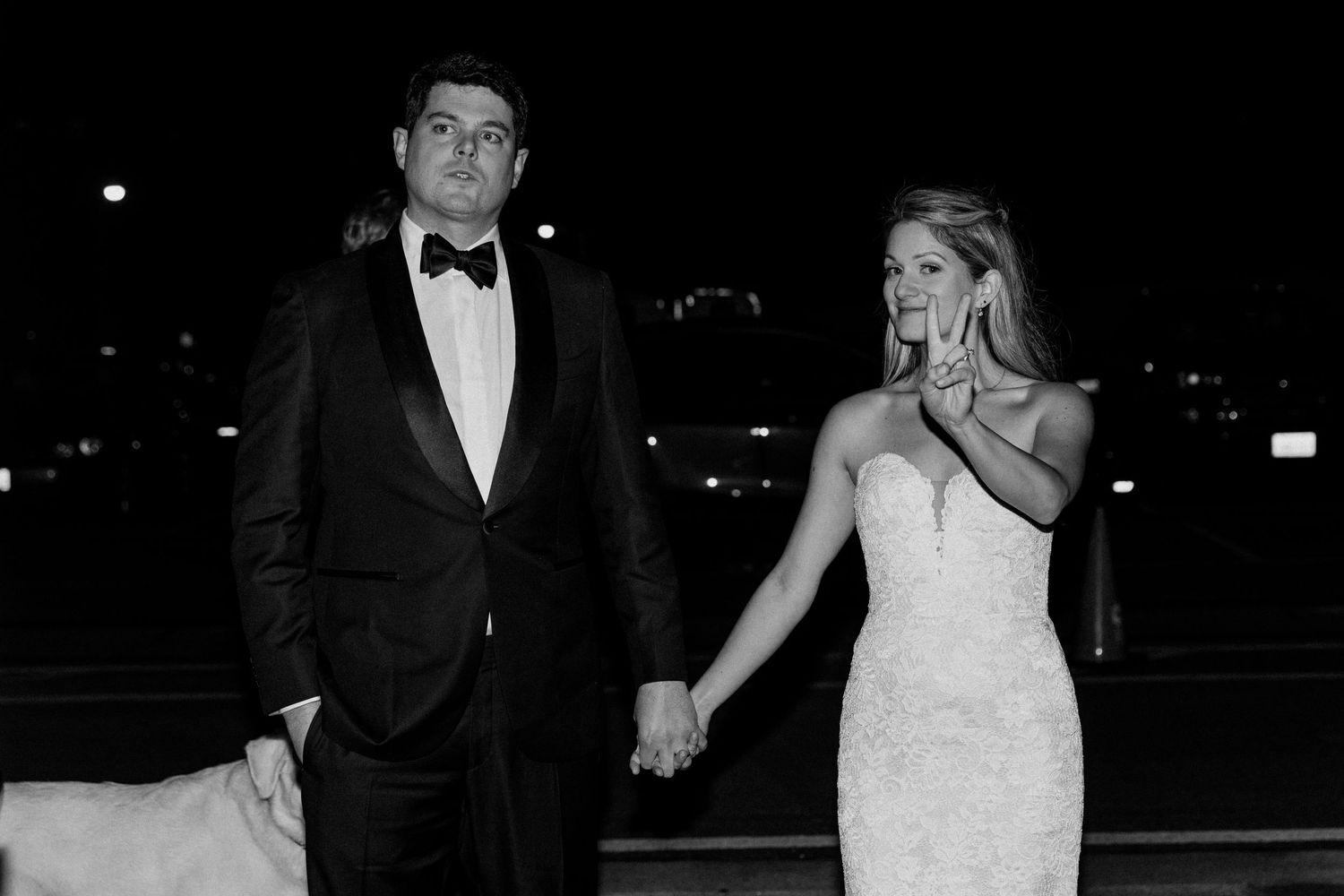 Elegant couple in formal wedding attire walking together at night.
