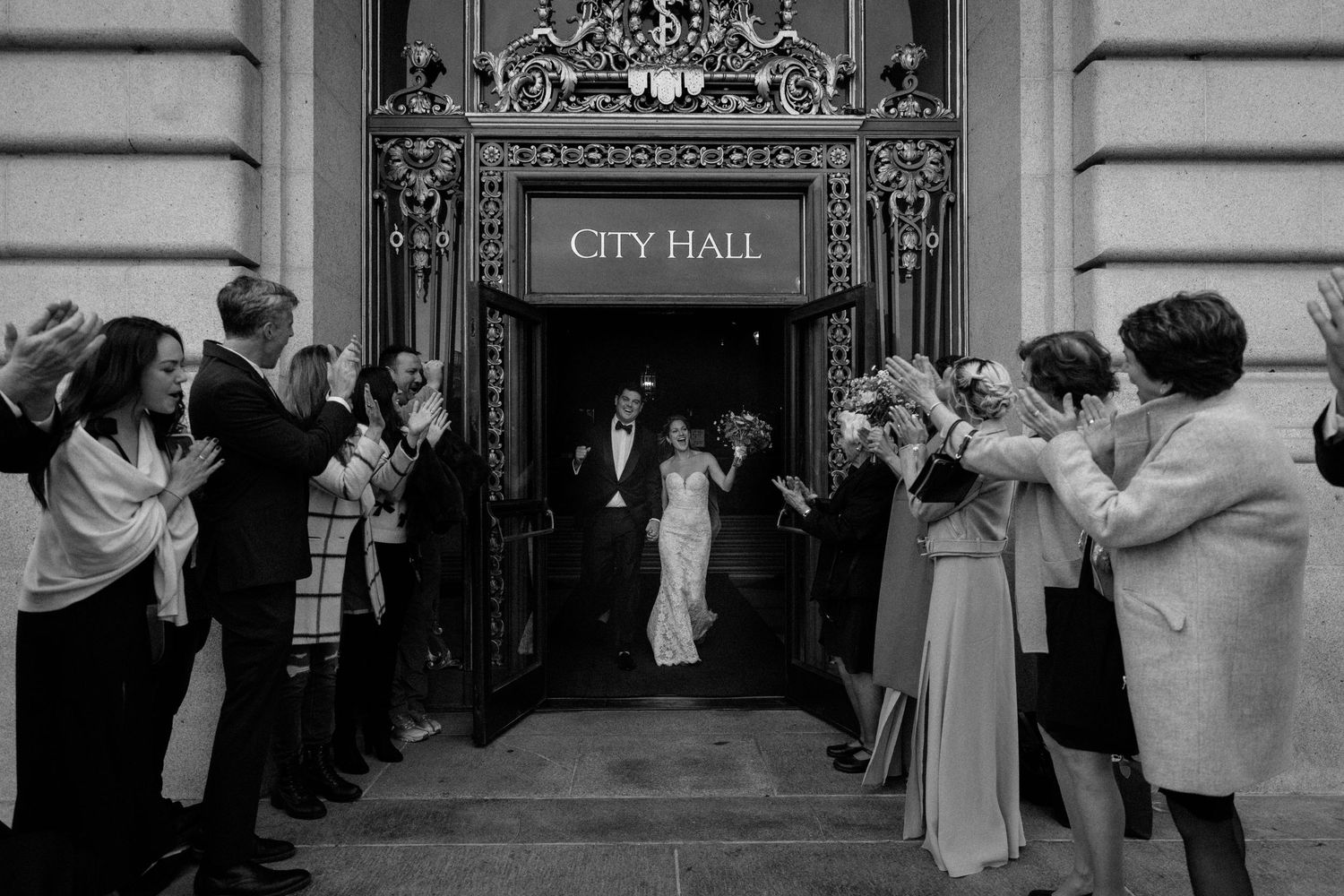 Black and white photo of wedding exit from City Hall with guests lining the doorway.