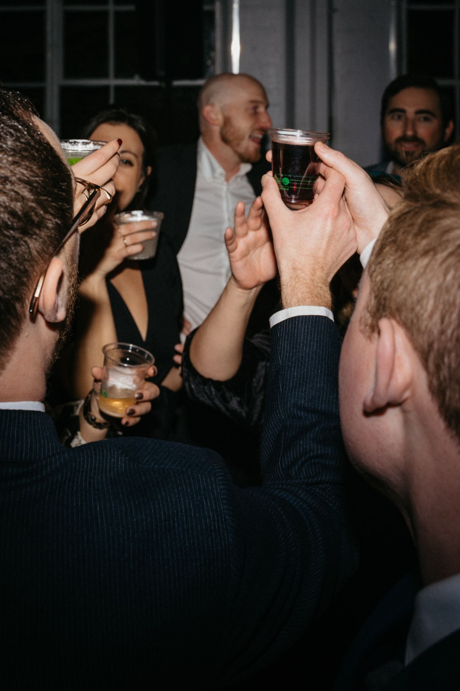Wedding guests raising drinks for a toast during celebration.