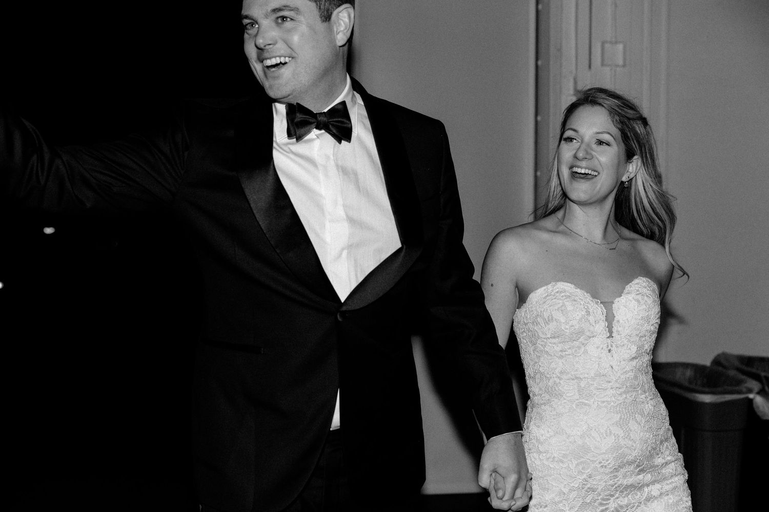A couple in wedding attire laughing together in black and white.