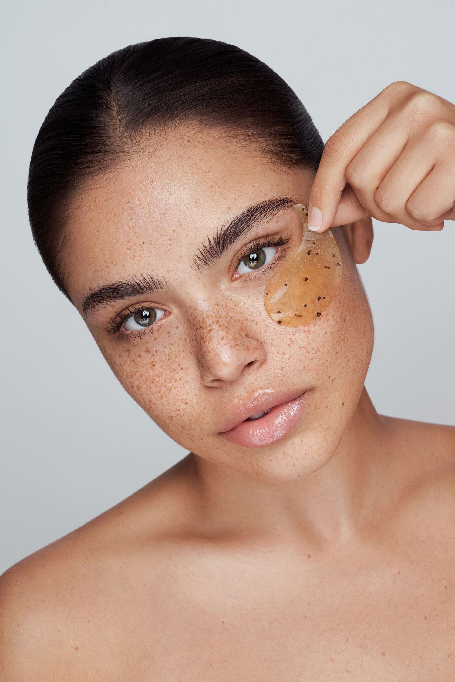 Closeup beauty shot showing natural freckles and skincare treatment dots under the eye.