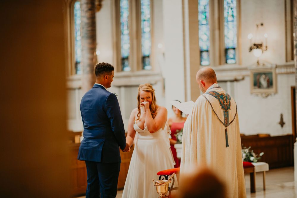 Emotional bride covers her mouth during heartfelt wedding vows in a beautiful church.