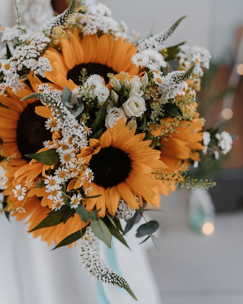 Close-up of vibrant sunflower wedding bouquet with white accent flowers.