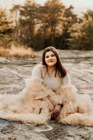 A dreamy portrait session featuring someone in a flowing champagne-colored tulle dress on rocky terrain.