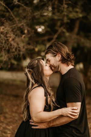 A romantic couple shares an intimate embrace against a dark autumn background.