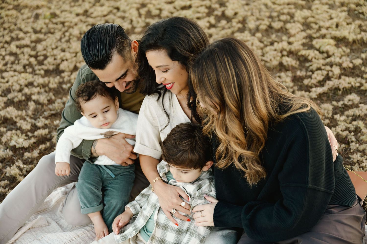 family photos by Ventura family Photographer, of family cuddled together on blanket in grassy field