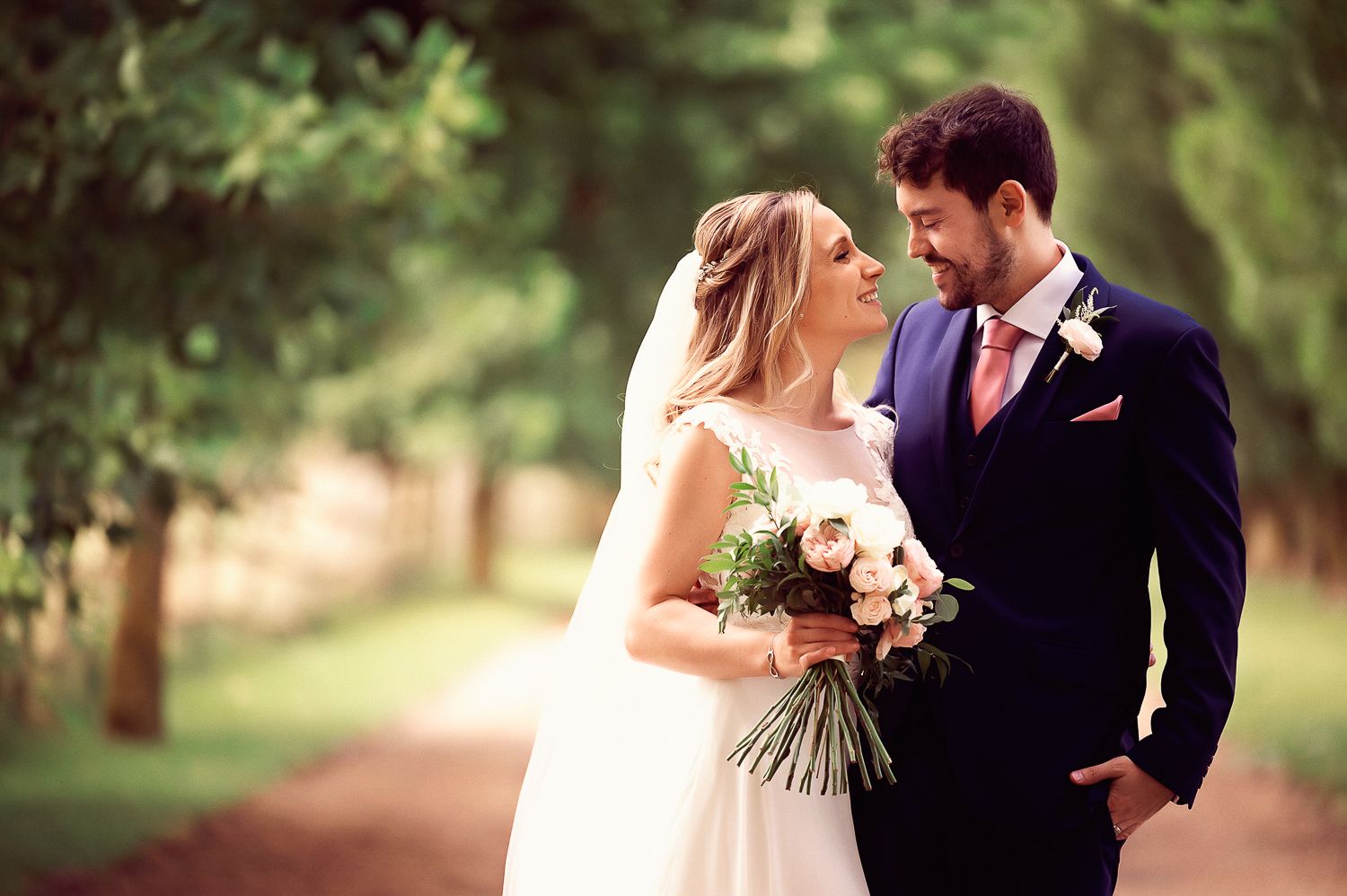 A romantic outdoor wedding portrait with a couple holding a bouquet.