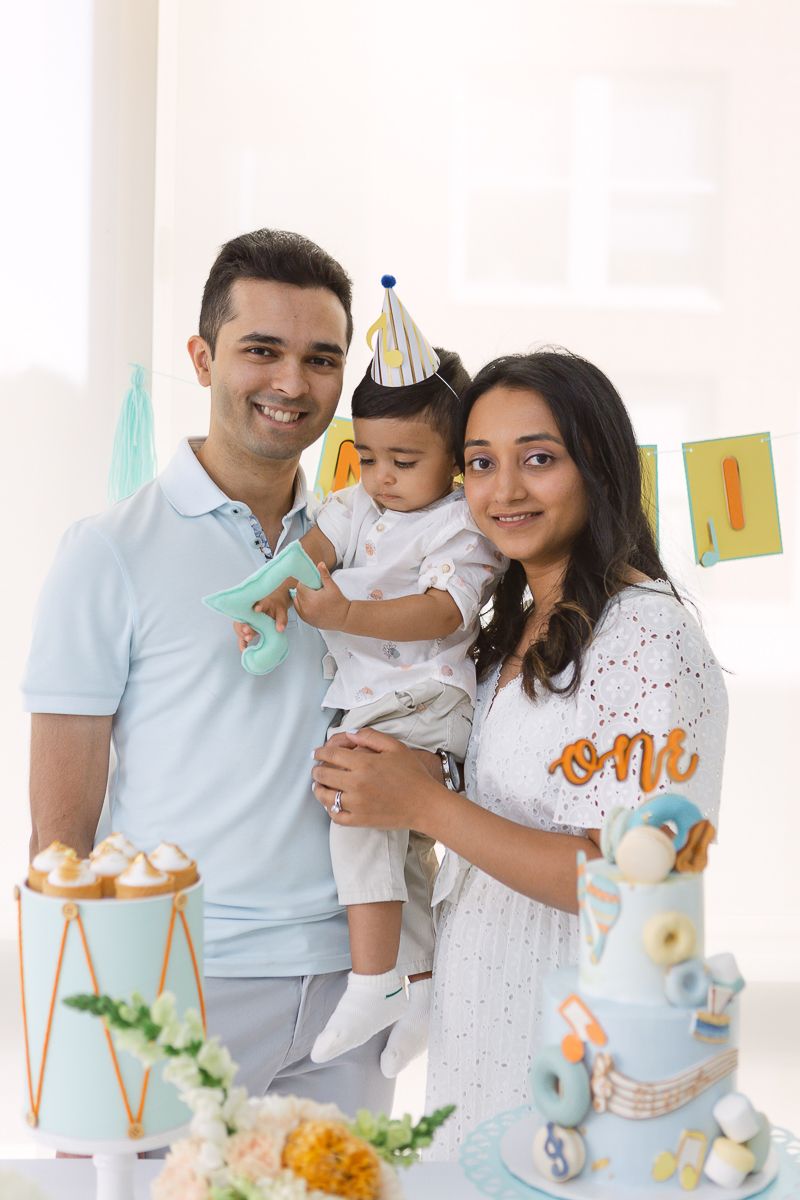 an indian couple with their one year old son on his birthday party with a bright white background photo by Paula Ortiz
