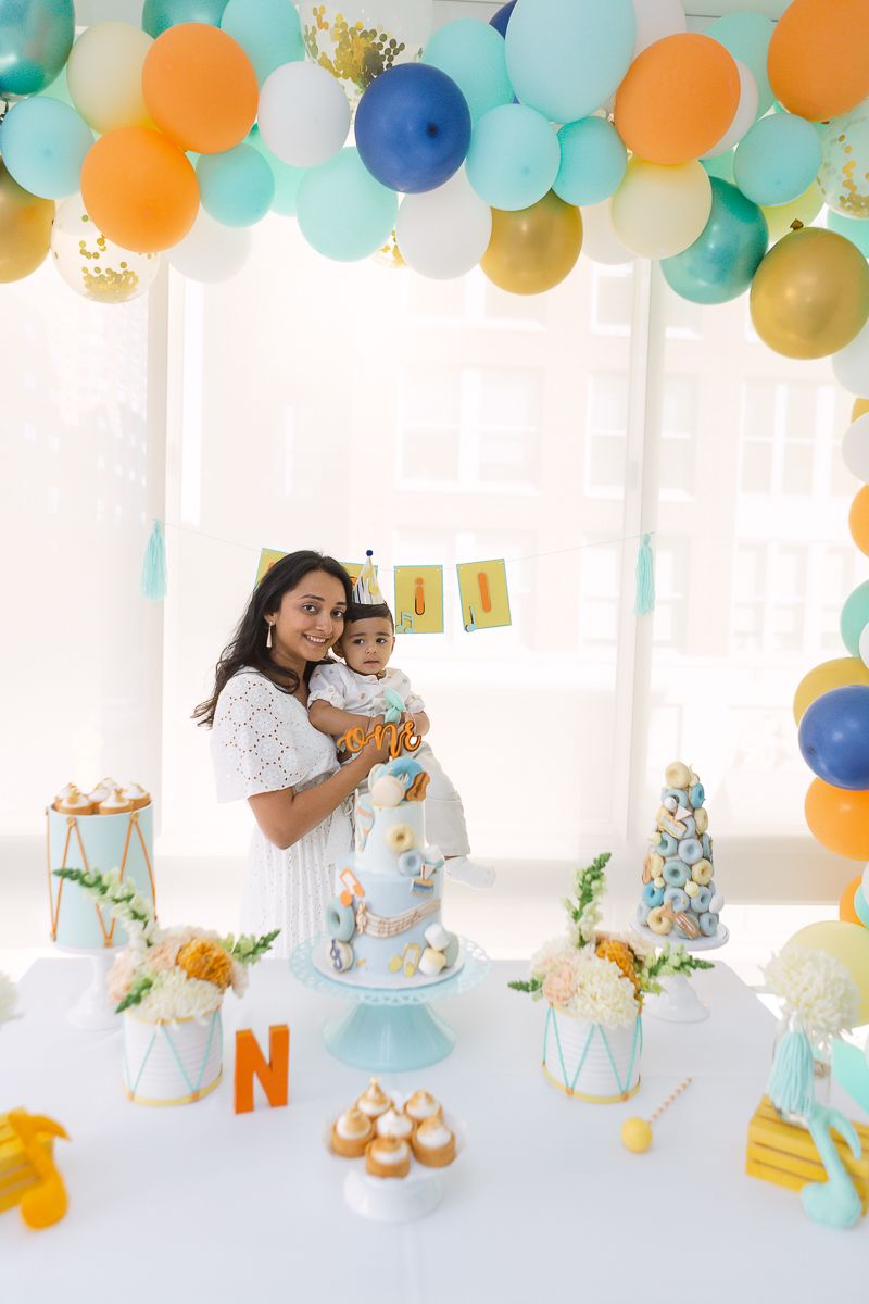 a mother holds his son during his birthday party in Hoboken while standing behind the decor photo by Paula Ortiz