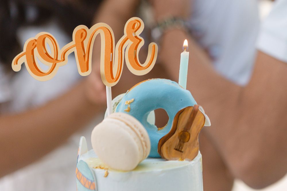 a close up detail view of a lit birthday candle and the word one on top of a cake during a birthday party in Hoboken
